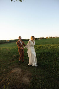bride and groom walking in a field 