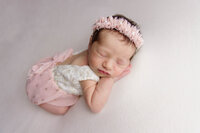 newborn baby girl laying on her hand in pink
