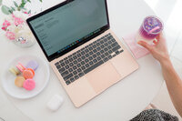 overview of white table with laptop, coffee, flowers and macaroons