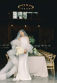 Bride in a wedding dress with a veil over her face standing in front of a decorated table