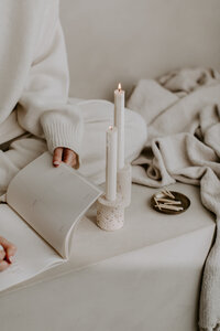 A woman in white reading a book by candle light 