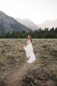bride running through the Grand Tetons and looking behind her 