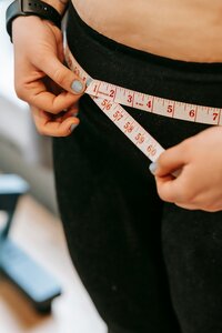 Woman measuring her waist with a tape measure