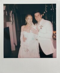 A polaroid film photo of a bride and groom showing off their wedding rings