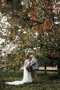 Dehlia and Nardus standing together under golden autumn leaves during their outdoor forest wedding portraits in Auckland, captured by wedding photographer Zanthe Vorsatz.