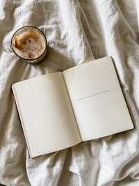 Brand photo of bullet journal notebook on a bed with coffee