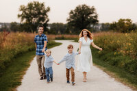 Two boys lead their parents on a gravel path.