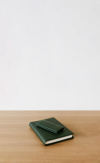 Two green leatherbound books in varying sizes sit atop one another, to represent alimony mediation.