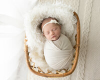 newborn baby girl wrapped in white swaddle for newborn photos