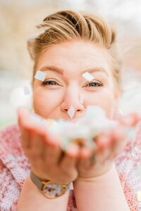 Becca Mai, Wedding Business Coach & Strategist blowing confetti into the camera