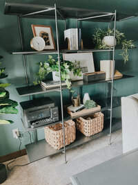 A large office bookshelf styled with baskets, books, and plants