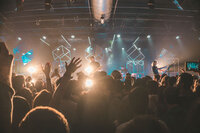 Fans at an outdoor music festival  dance  with lights and confetti
