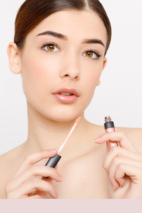 A woman holds a container of Pink Bridal Lip gloss