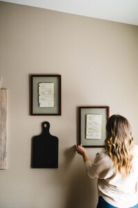 woman styling photos on her wall