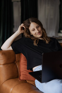 A person lounging on a couch with a laptop on their lap 