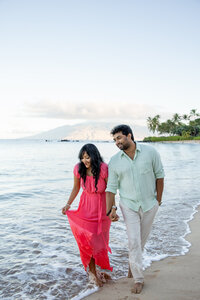 Hawaii Engagement Photographer captures couple walking through water holding hands during beach engagement photos