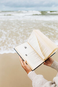 holding an open book at the beach