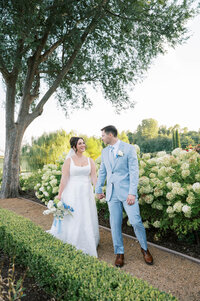 Bride and groom walking through a hydrangea garden during an elegant estate wedding in Oklahoma