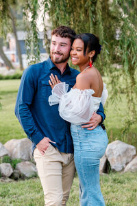 Couple poses for couple portrait with weeping willow branches in the background