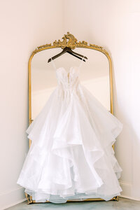 White wedding ballgown hanging on hanger in front of a mirror
