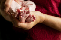 Woman holding newborn feet.