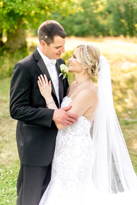 A bride and groom gaze at each other on a summer day.