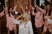 bride drinking from champagne bottle while getting ready