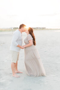 pregnant couple kissing on the beach