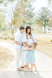 pregnant mom holding baby bump in white maternity dress at Cutter Creek Golf Course near Greenville, NC