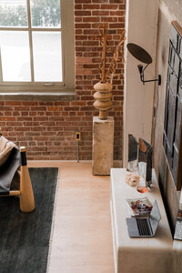 Loft studio gathering room with dresser arranged with Macbook Pro laptop, Instyle magazine, a glass of juice, and other decorative elements
