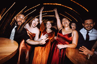 A group of wedding guests party on a dance floor under beautiful light streaks