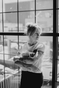 woman holds books in front of window