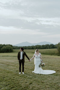 Bride and groom holding hands in front of Sharp Top and Flat top, part of the Blue Ridge mountains