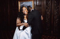 A black bride and groom embrace in a formal lounge room