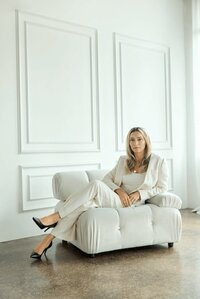 woman lounging in a chair in front of a french wall
