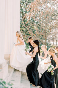 Bride walking up steps with bridesmaids in black dresses