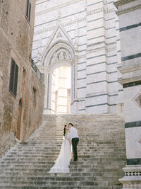 a bride and groom walking up the steps to the Siena Cathedral in Italy
