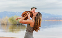 mom holding baby up in the air and giving her a kiss on the cheek during photos