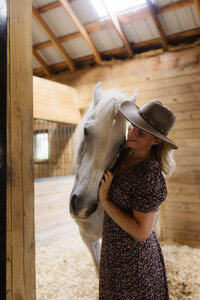 Woman standing beside her horse in the barn at Peace Horse Collective, offering heart-centered support for horse owners seeking deeper connection in the Berkshires