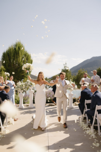 couple holding hands and smiling as they walk back down the aisle after ceremony
