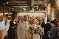 A newlywed couple walking while guests toss flower petals over them 