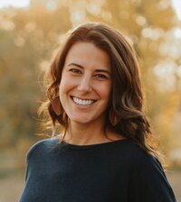 Zoe Schroeder, a nutrition expert, is seated at a table with a laptop and a notebook, engaged in her professional tasks.