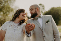 Mariés les yeux dans les yeux montrant leur alliance en premier plan, lors d'une séance photo avec Laura et Clément, photographe et vidéaste de mariage.