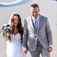 Newlywed couple smiling and holding hands during their wedding ceremony, featured in Amy and Kristopher’s review of White House Wedding Photography.