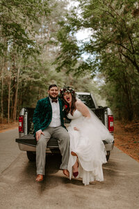 Man and woman in back of a pickup truck looking at the camera laughing
