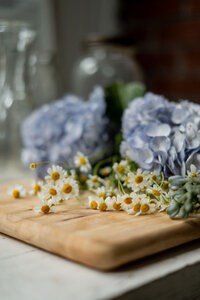Mix of large and small florals sitting on a wooden block on table