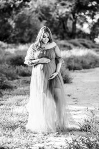 Outdoor family maternity photoshoot with everyone hugging .