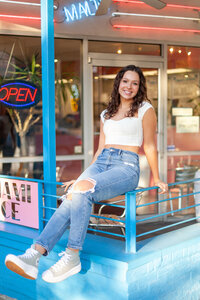 Senior pictures of a girl at ice cream shop dangling feet