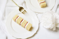 Slice of madagascan vanilla bean and raspberry cake on a plate with gold fork