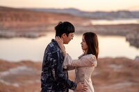 A couple engaged with the dramatic red rock cliffs of Lake Powell rising behind them, capturing a picture-perfect moment.